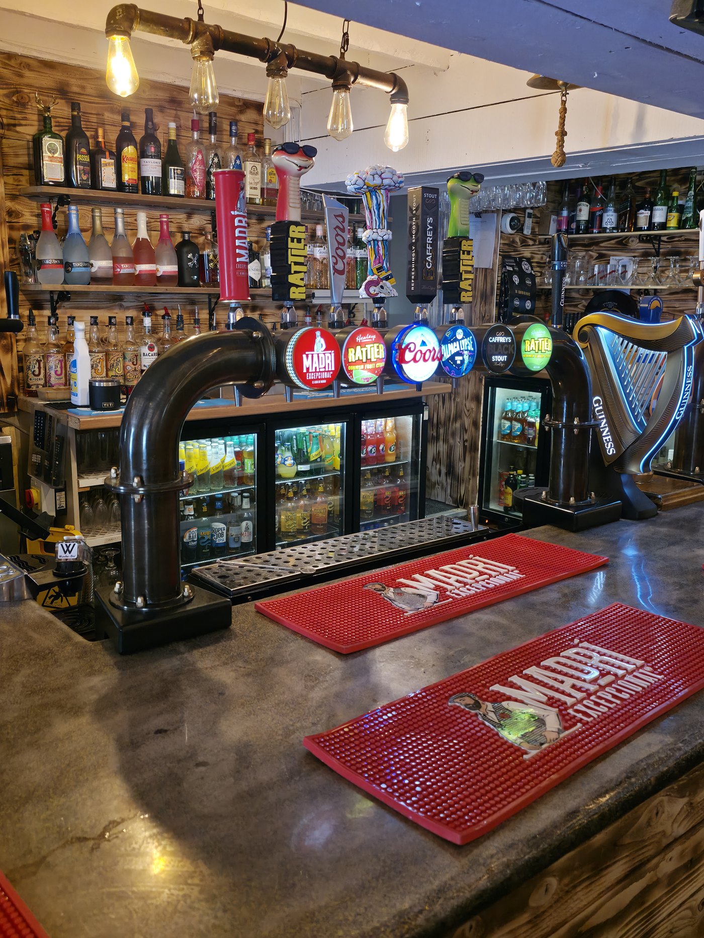 The bar at The Quintrell Inn, with hand-pulled ale taps, a range of drinks and warm Edison-bulb lighting